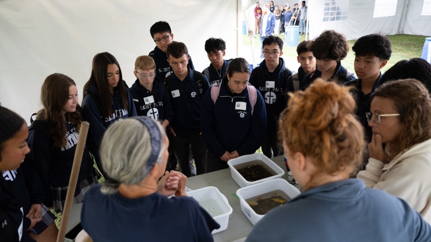 A group of students gather around a table to look at benthics.
