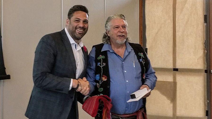 Board chair shakes hand of Metis partner
