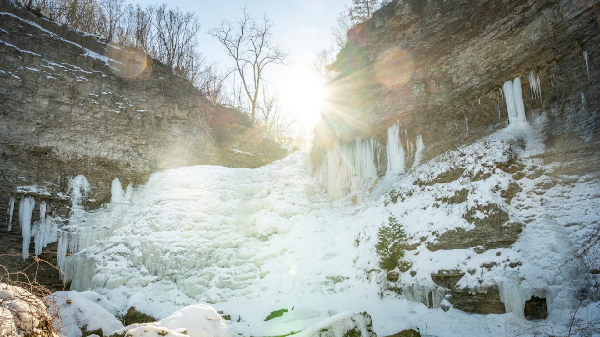 a frozen waterfall with the sun peaking over the top