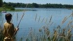 A young boy stands on the banks of Dils Lake, fishing.