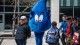 A waterdrop mascot waves at a group of young children.
