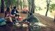 Friends outside of their tent make breakfast in the woods.
