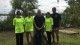 Group of students and staff wearing green with a background of nature and lake
