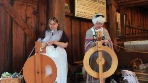 Two ladies demonstrating handweaving and spinning with equipment