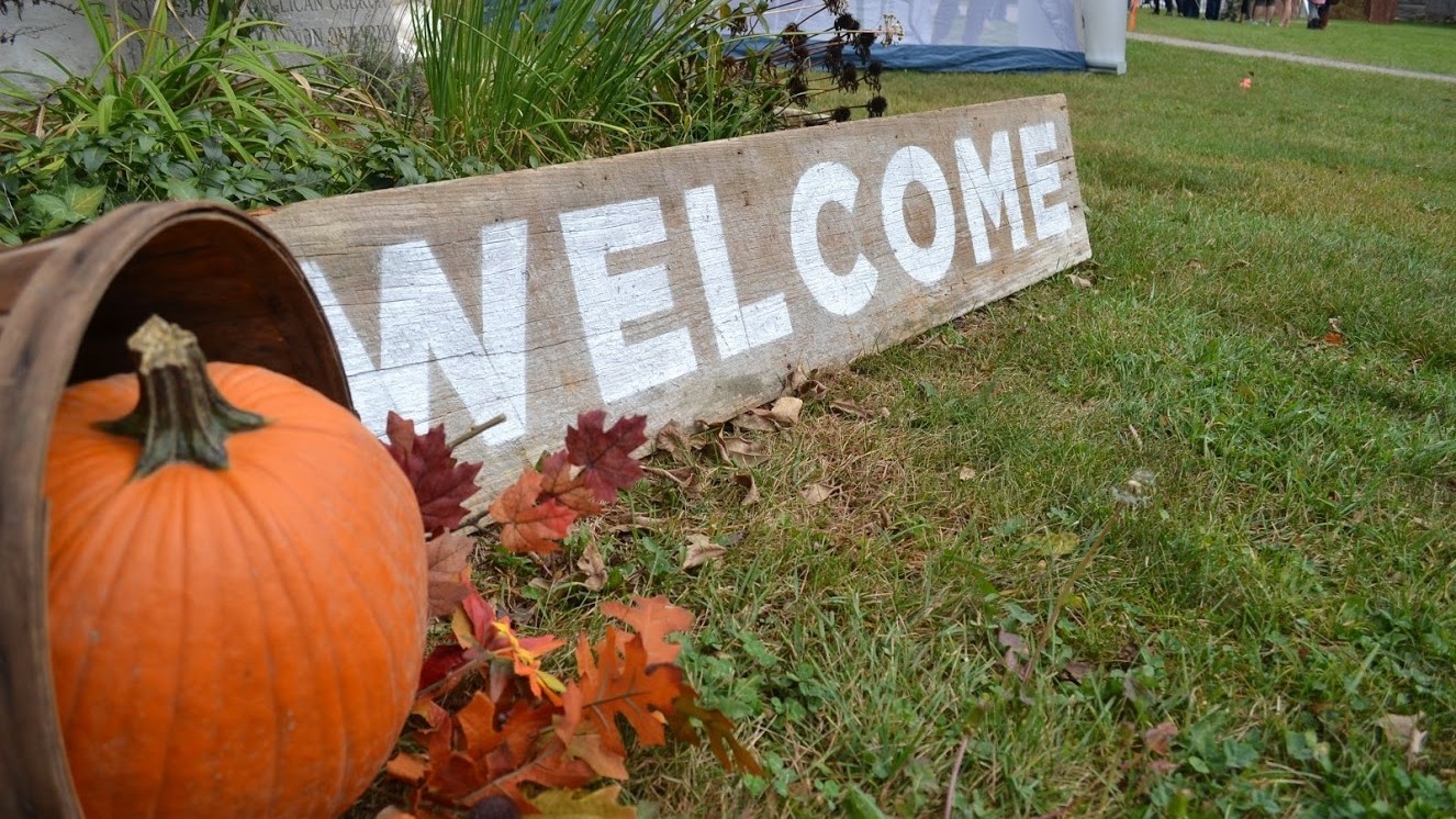 Pumpkin on glass with wooden welcome sign