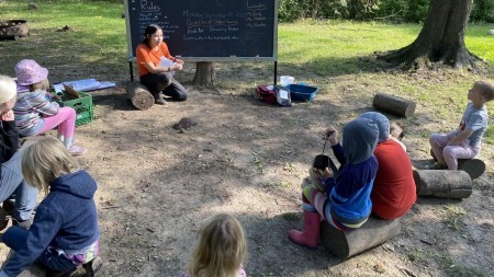 Photo of children learning about nature, gathered around a circle