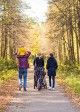 Family walk down path with child on shoulders