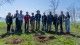 A group of staff and leaders from NPCA, NPCF, and the Town of Fort Erie stand outdoors with shovels during a tree-planting event, surrounded by trees and greenery.