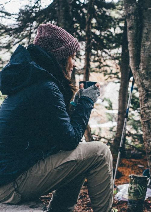 Young girl sips coffee in woods.