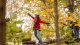 Girl in red sweater walking on wood bridge amongst the trees