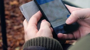 Hand holding cellphone in woods