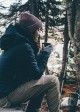 Young girl sips coffee in woods.